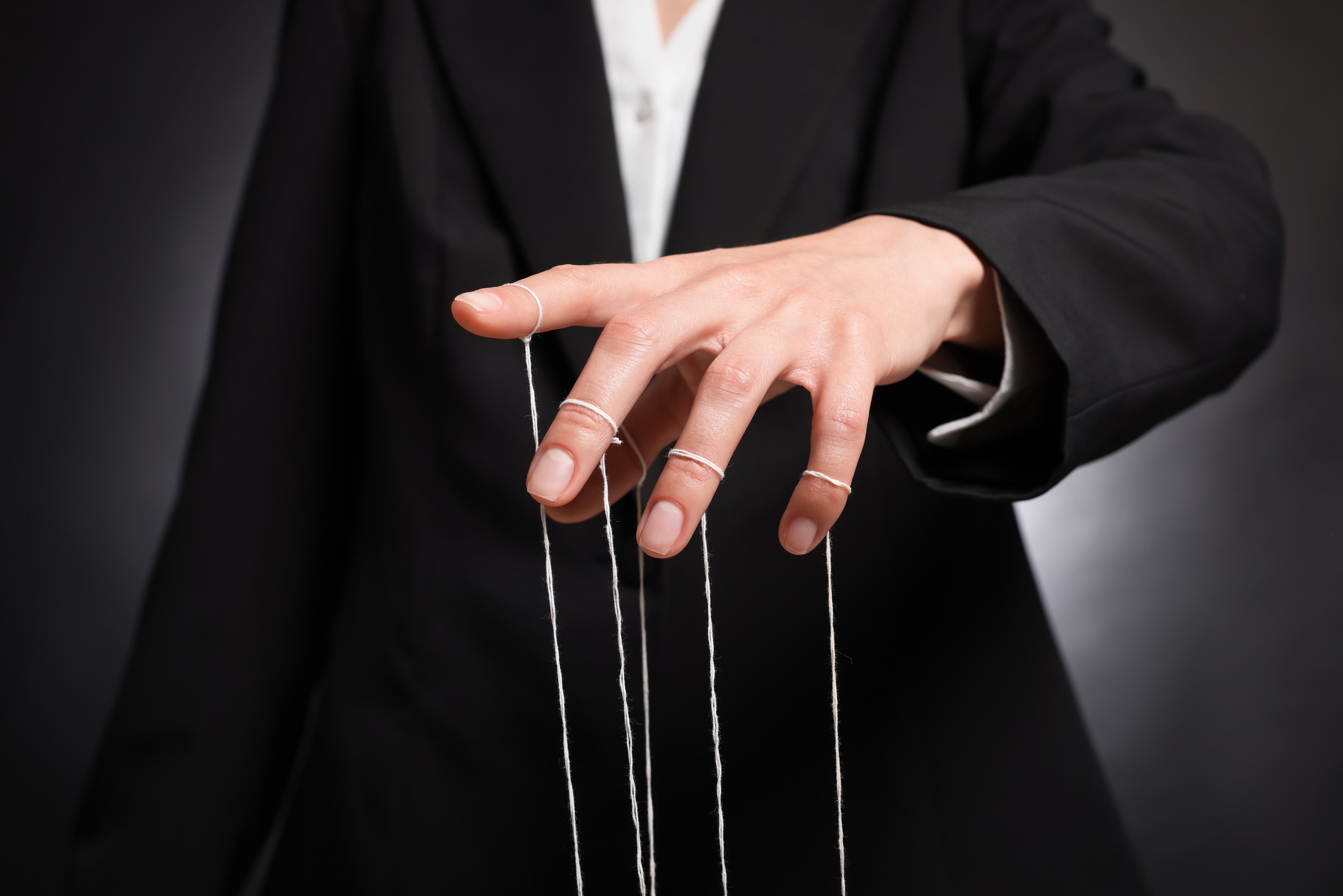 Manipulacja - dłoń pociągająca za sznurki marionetki